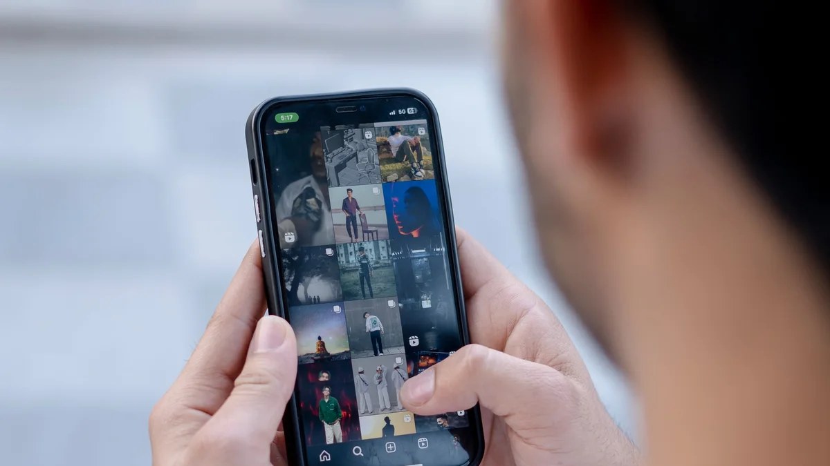 Pessoa examina um smartphone segurando o aparelho com as duas mãos.