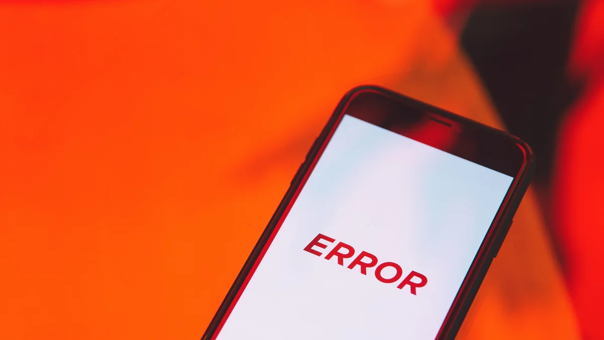 Celular exibe uma mensagem de erro sobre uma superfície vermelha.