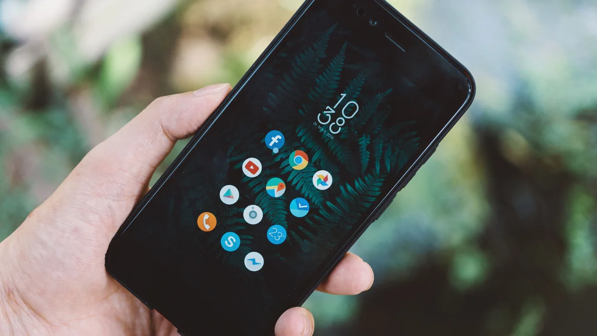 Pessoa segura um smartphone com aplicativos visíveis na tela.