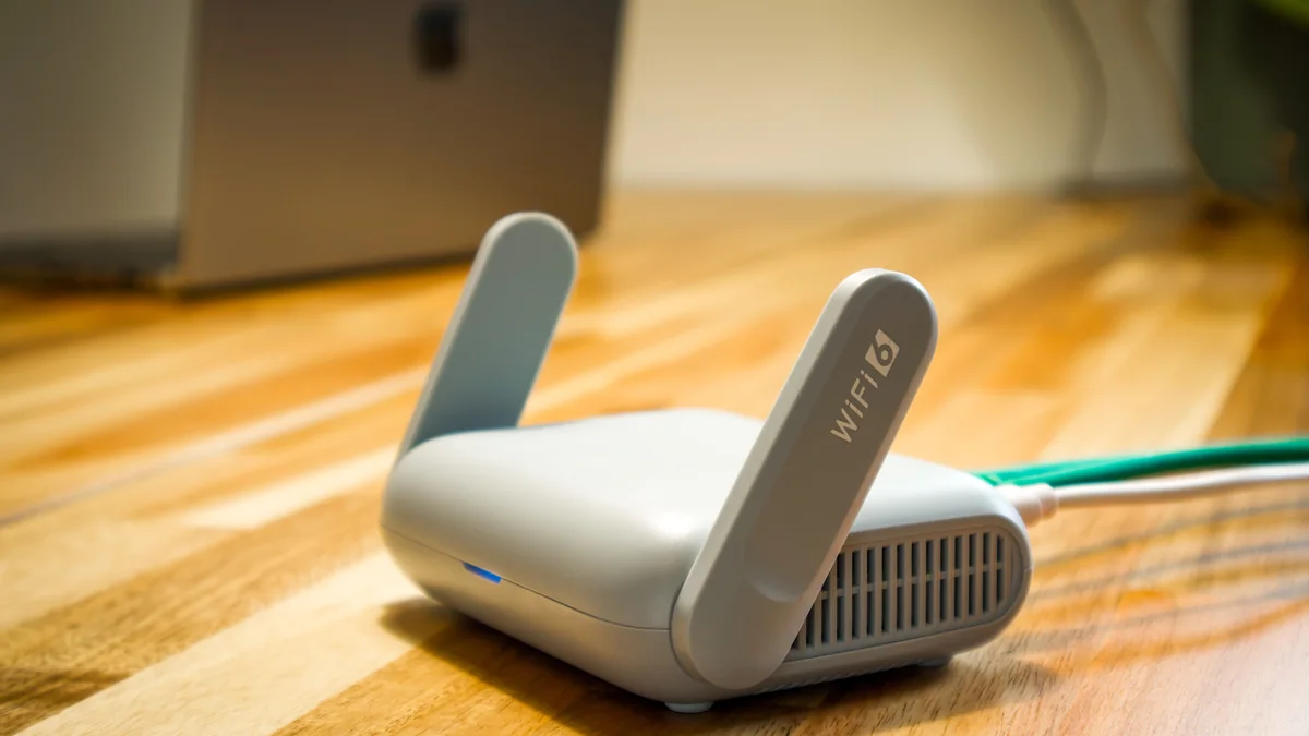 Roteador sem fio com antenas e cabo sobre uma mesa.