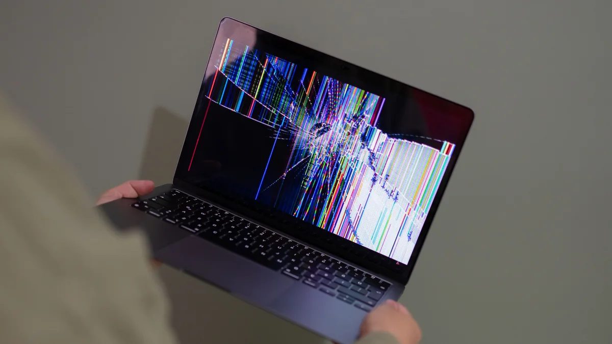 Pessoa segura notebook com falha visual na tela.