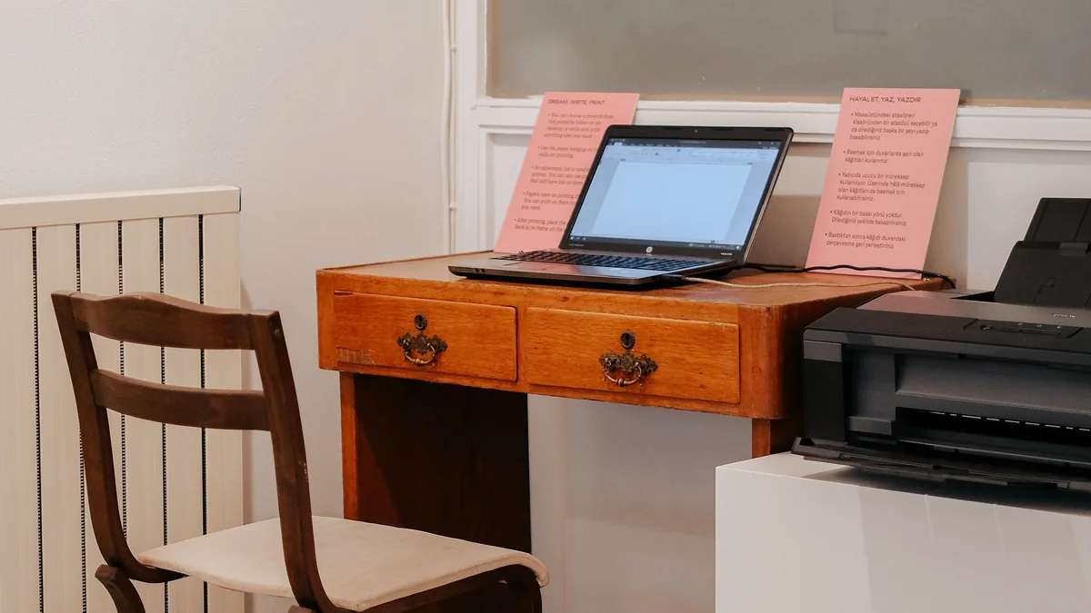 Notebook e impressora no mesmo ambiente de trabalho.